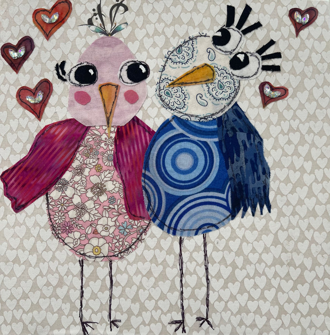 Whimsical bird artwork made with layered fabric and mixed media, featuring companion birds in soft cream and muted blue  and pink tones with textured stitched  looking details