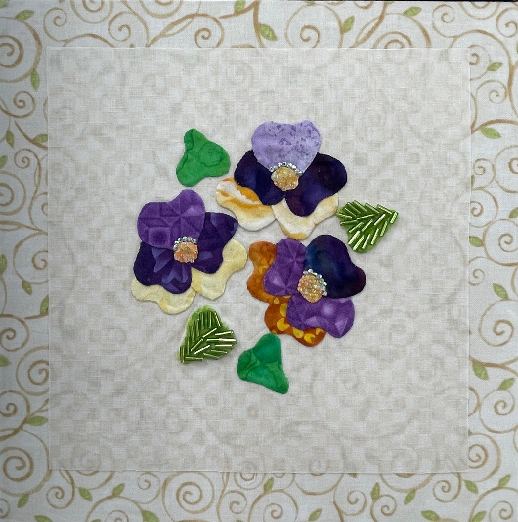 8 x 8 fabric collage artwork featuring a cluster of purple and cream flowers with beaded centers made from inherited textiles