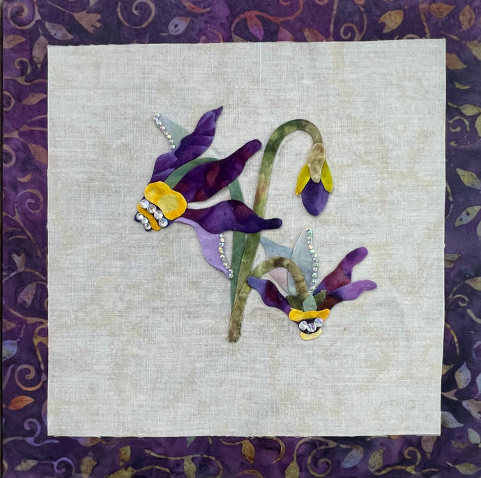 8 x 8 fabric collage artwork featuring purple and lavender flowers with curved stems and crystal embellishments made from inherited textiles