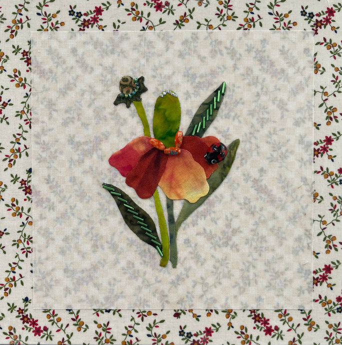 Floral quilt block with a red flower and green leaves on a textured fabric background.