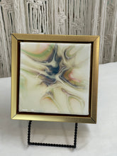 Quiet Tide resin artwork featuring soft luminous pearl, gold, blue, and soft green color-shifting pigments flowing across a glossy abstract surface in a floating frame.