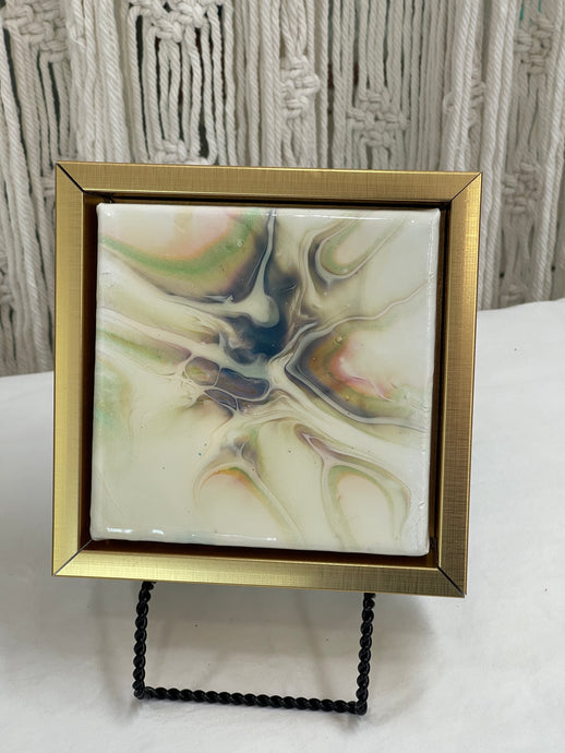 Quiet Tide resin artwork featuring soft luminous pearl, gold, blue, and soft green color-shifting pigments flowing across a glossy abstract surface in a floating frame.