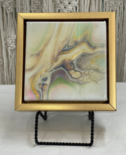 Shifting Current abstract resin artwork with flowing luminous pearl, blue, gold, and green pigments in a gold floating frame.