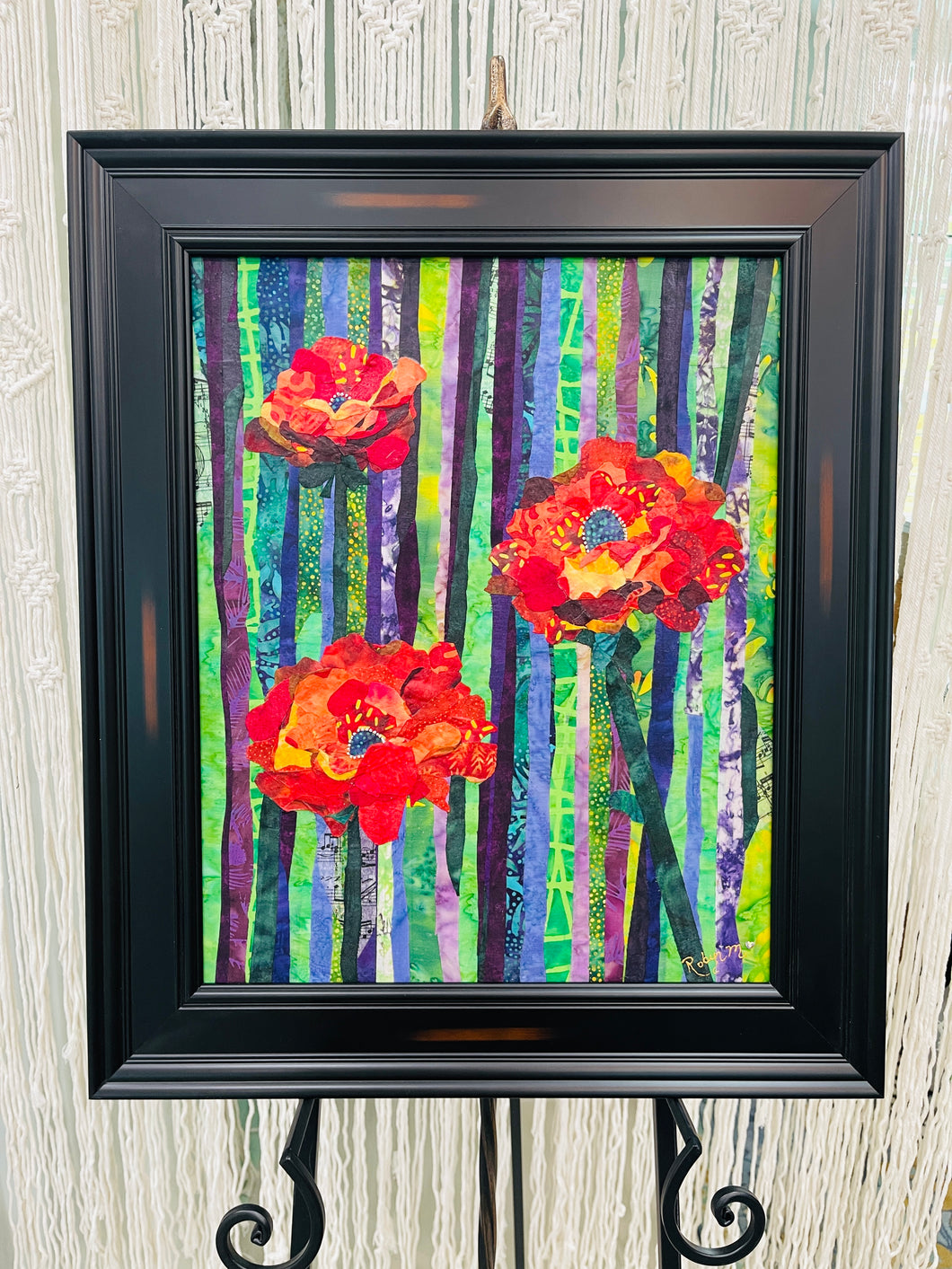 Original all fabric floral collage artwork 20x16 inches, three bold poppy blooms in crimson burnt orange and golden yellow batik fabric with Swarovski crystals against vertical striped batik background in purple lavender green and yellow, presented in deep black frame, part of the Floral and Botanical Collection by Robyn Moore Arts